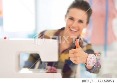 Closeup on seamstress with sewing machine showing thumbs up Closeup on seamstress with sewing machine showing thumbs up 17180053
