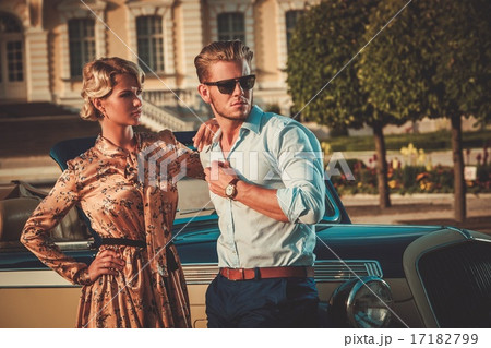 Wealthy couple near classic convertible against royal palace 17182799