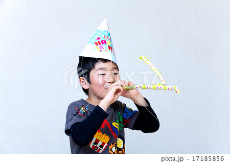 誕生日の三角帽子を被ってピロピロ笛で遊ぶ男の子 17185856