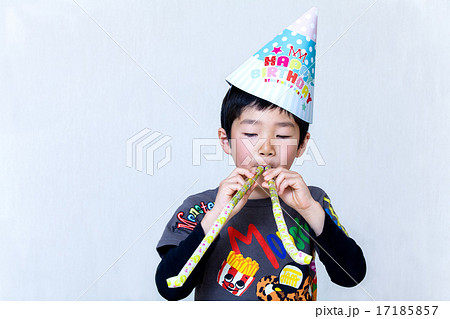 誕生日の三角帽子を被ってピロピロ笛で遊ぶ男の子 17185857