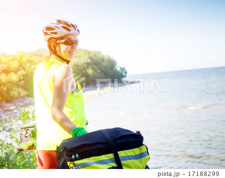 Young woman with bicycle standing on seaside 17188299