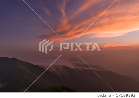 山肌を流れる雲と夕日に染まる雲 17199592