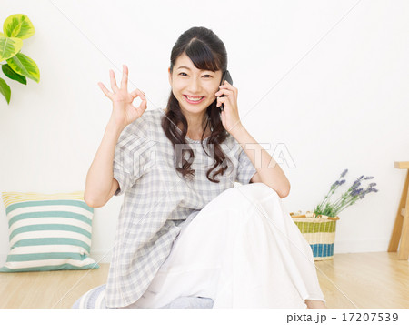 部屋でスマートフォンで話す女性　OKサイン 17207539