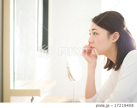 美容・鏡を見る若い女性 17219408