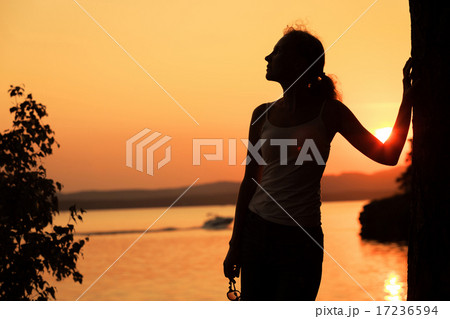Silhouette of happy woman who standing on the coast of lake 17236594