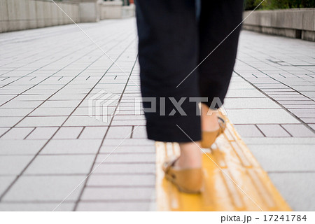 歩道の誘導ブロックの上を歩く女性 17241784