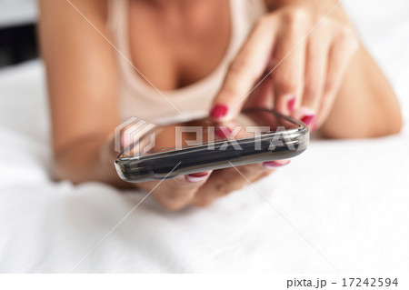 young woman using a smartphone in bed 17242594