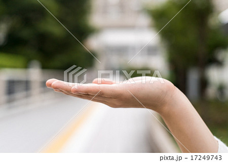 歩道で手のひらを上に向ける女性の写真素材