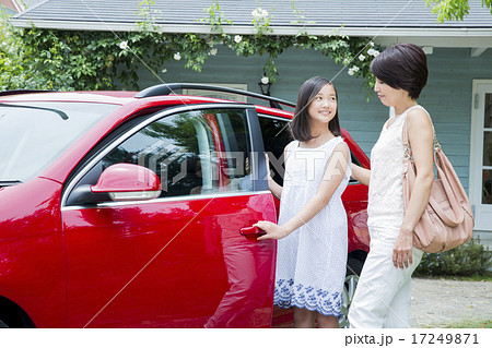 車の横に立つ10代の女の子とお母さんの写真素材