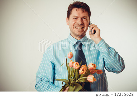 Businessman smiling while phoning, holding tulips 17255028