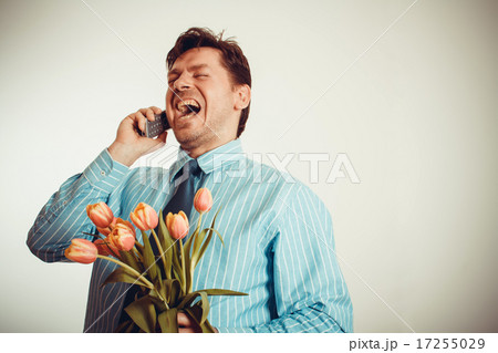 Businessman smiling while phoning, holding tulips Businessman smiling while phoning, holding tulips 17255029