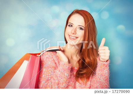 Redhead girl with shopping bags on blue background. Redhead girl with shopping bags on blue background. 17270090