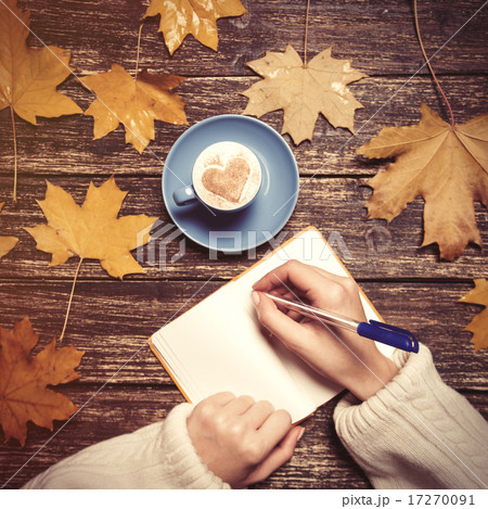 Female hand writing something in notebook near cup of coffee. 17270091