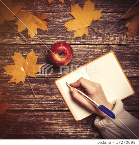 Female hand writing something in notebook next to apple 17270098