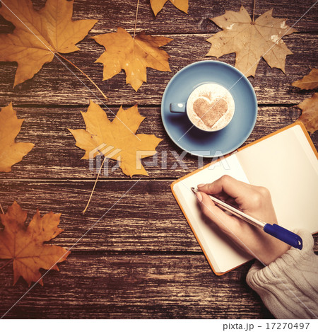 Female hand writing something in notebook near cup of coffee. 17270497