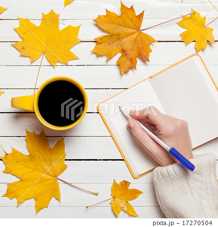 Female hand writing something in notebook near cup of coffee. 17270504