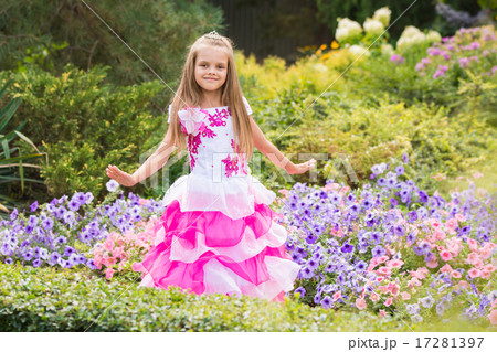 Happy little girl in a pink dress at flower bed 17281397