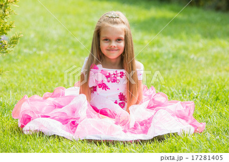 Five-year girl in a beautiful dress sat on the lawn in the green garden 17281405