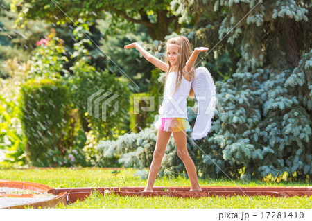 Girl with angel wings in the garden enjoys splashes of water 17281410
