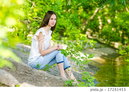 A girl sits on the concrete bank of the river 17281453