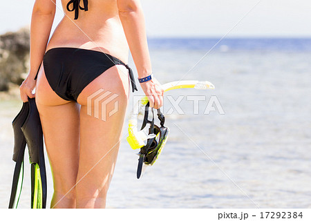 Young woman holding snorkeling gear looking at the sea Young woman holding snorkeling gear looking at the sea 17292384