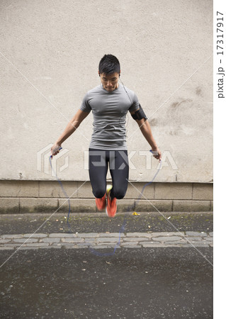 Asian man using a skipping rope in a city street. Asian man using a skipping rope in a city street. 17317917