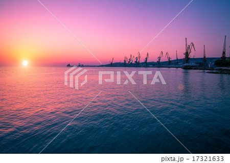 Sunrise over stone beach with port 17321633