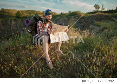 Young caucasian man with backpack sitting on the top of hill Young caucasian man with backpack sitting on the top of hill 17331992
