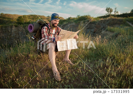 Young caucasian man with backpack sitting on the top of hill 17331995