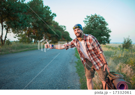 Young smilimg caucasian tourist hitchhiking along a road. Young smilimg caucasian tourist hitchhiking along a road. 17332061