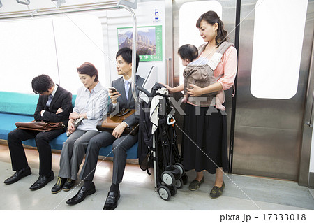 抱っこ紐をして電車に乗る若い女性の写真素材