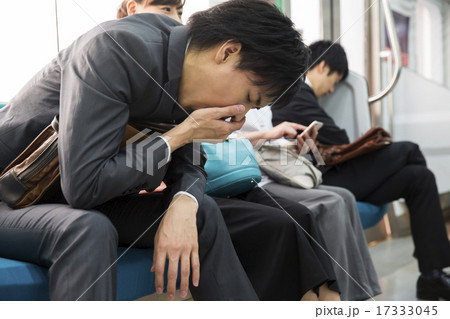 電車内で口に手を当てるビジネスマンの写真素材