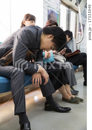 電車内で熟睡するビジネスマンの写真素材