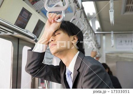 電車内で立ったまま寝るビジネスマンの写真素材