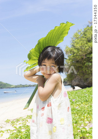 南国少女 リゾート 夏イメージ 大きい葉っぱを持った女の子の写真素材