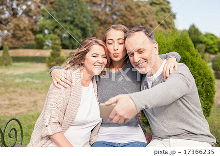 Pretty mature family is photographing themselves in park Pretty mature family is photographing themselves in park 17366235