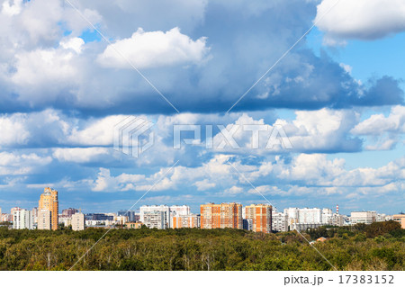 low blue clouds over green forest and city 17383152