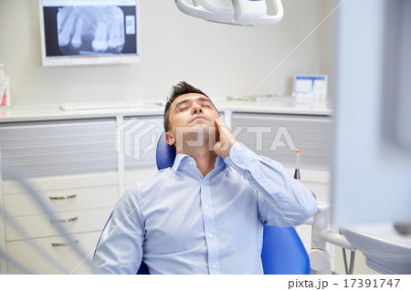 man having toothache and sitting on dental chair man having toothache and sitting on dental chair 17391747