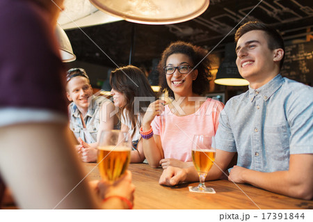 happy friends drinking beer and talking at bar 17391844