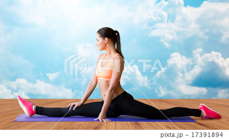 smiling woman doing splits on mat over clouds smiling woman doing splits on mat over clouds 17391894