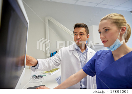 dentists with x-ray on monitor at dental clinic dentists with x-ray on monitor at dental clinic 17392005