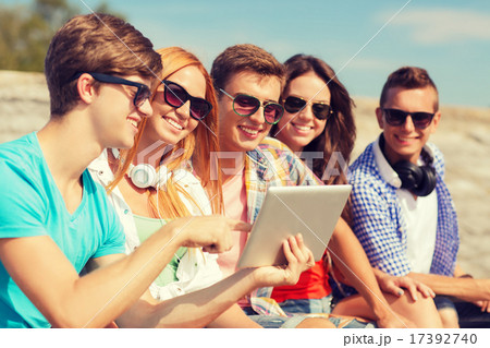 group of smiling friends with tablet pc outdoors 17392740