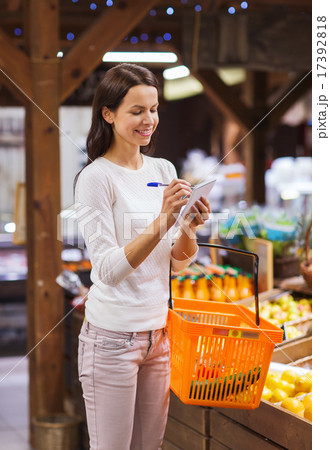 happy woman with food basket and notepad in market 17392818