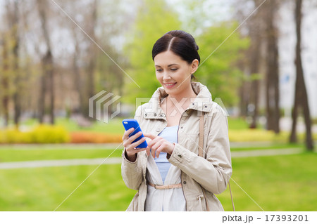 smiling woman calling on smartphone in park smiling woman calling on smartphone in park 17393201