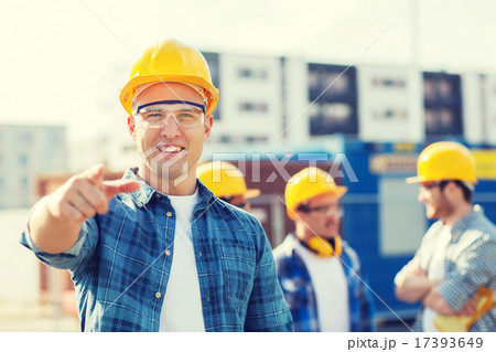 group of smiling builders in hardhats outdoors group of smiling builders in hardhats outdoors 17393649