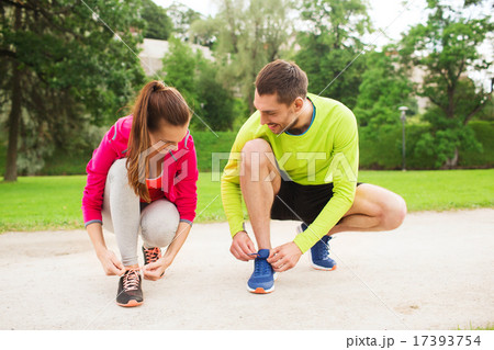 smiling couple tying shoelaces outdoors 17393754
