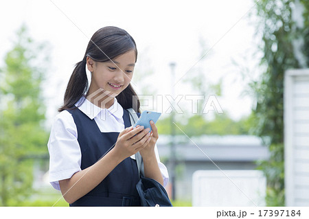 スマホを操作する制服姿の中学生の女の子の写真素材