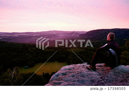 An sportsman sit on a rock and watch to landscape 17398505