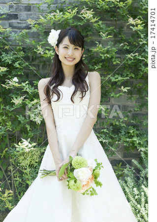 ウェディングドレス姿でブーケを持ち中庭に立つ若い女性 17414701