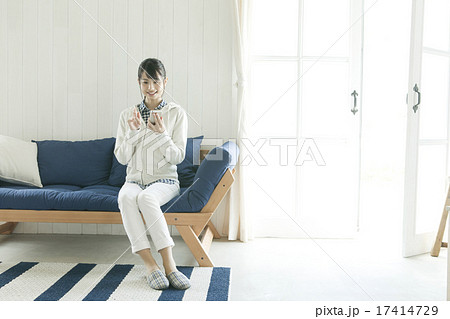ソファに座ってスマホを操作する若い女性の写真素材 17414729 Pixta